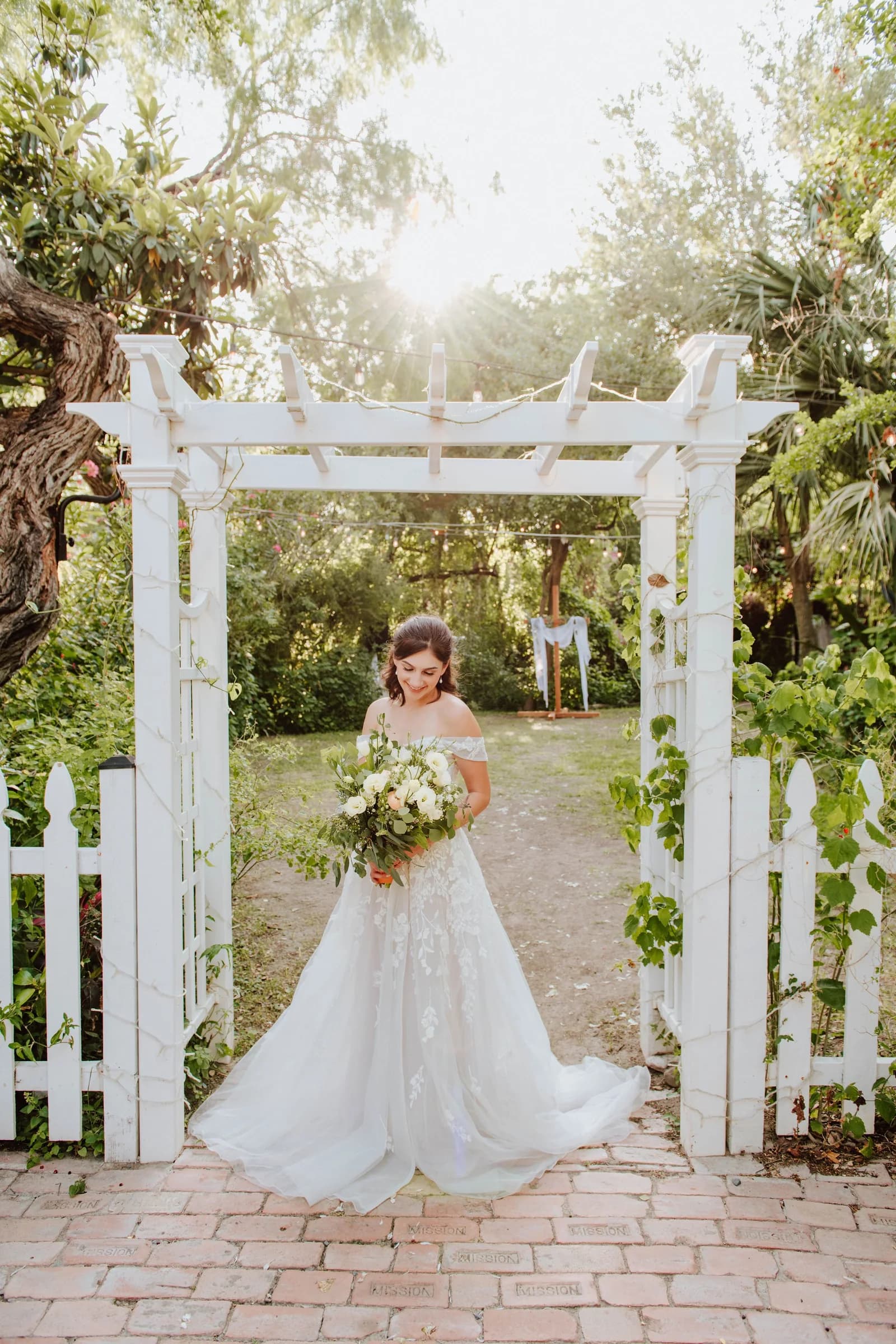 Flower girl standing beneath the outdoor ceremony arbor